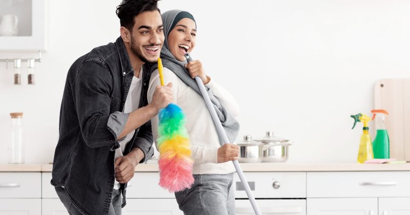 Joyful muslim couple cleaning floor and having fun in kitchen Beautiful joyful muslim young couple cleaning floor and having fun in kitchen together, full length photo, copy space. Funny lady in hijab and her singing boyfriend house-keeping their new house