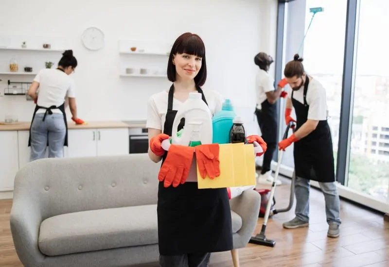 Portrait of young Caucasian woman professional cleaning worker holding a bucket for washing with detergents on bright kitchen studio background, copy space.